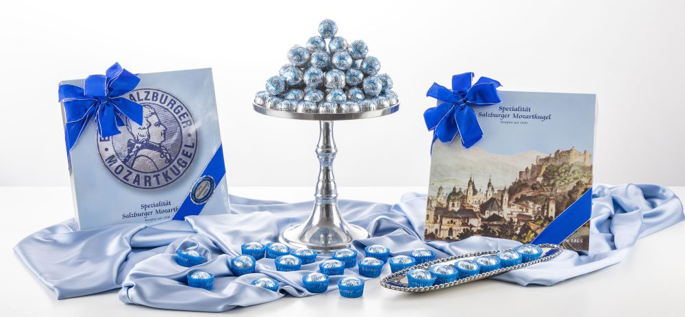 Echte Salzburger Mozartkugeln in blauer Folie auf Silbertablett und Geschenkverpackungen